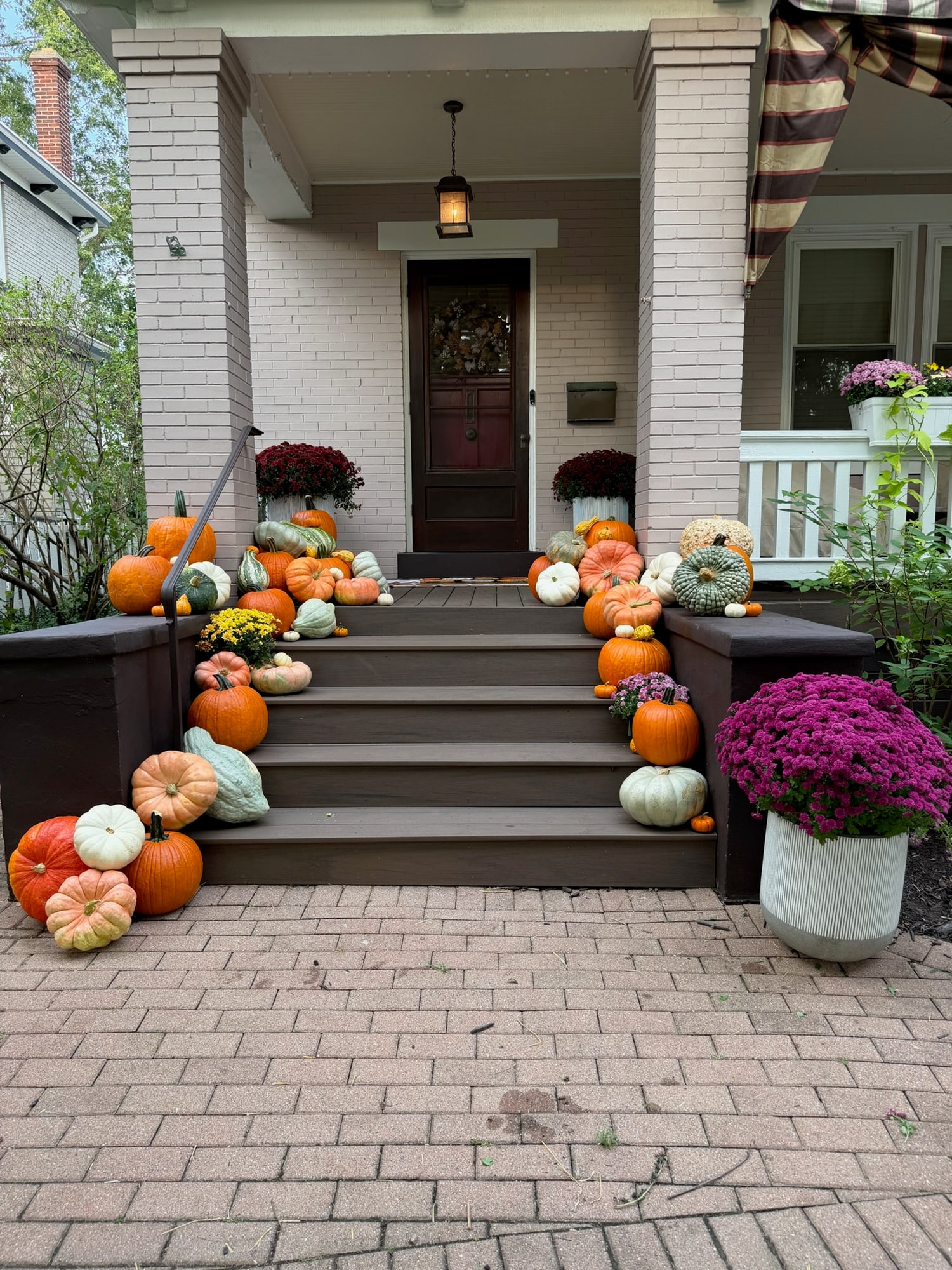 The full Mount Lookout porch from the walk, with pumpkins down both sides of the steps and purple mums in a planter at the right