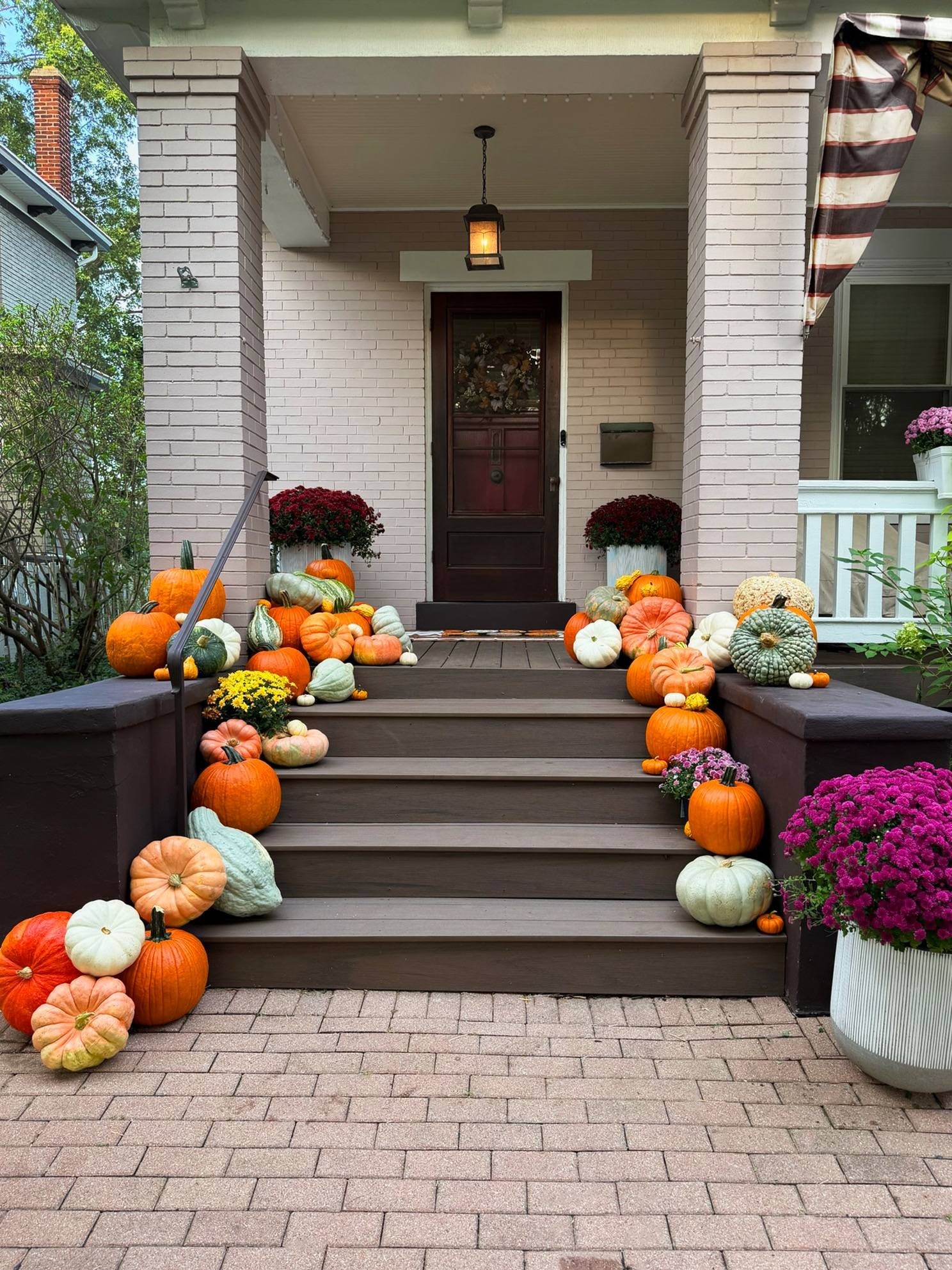 Orange, white, green and heirloom pumpkins down both sides of the Mount Lookout steps, with burgundy mums beside the front door and magenta mums in a white planter